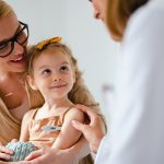 Medico pediatra che controlla la temperatura della bambina in visita presso il suo studio e che ha diritto all’esenzione ticket