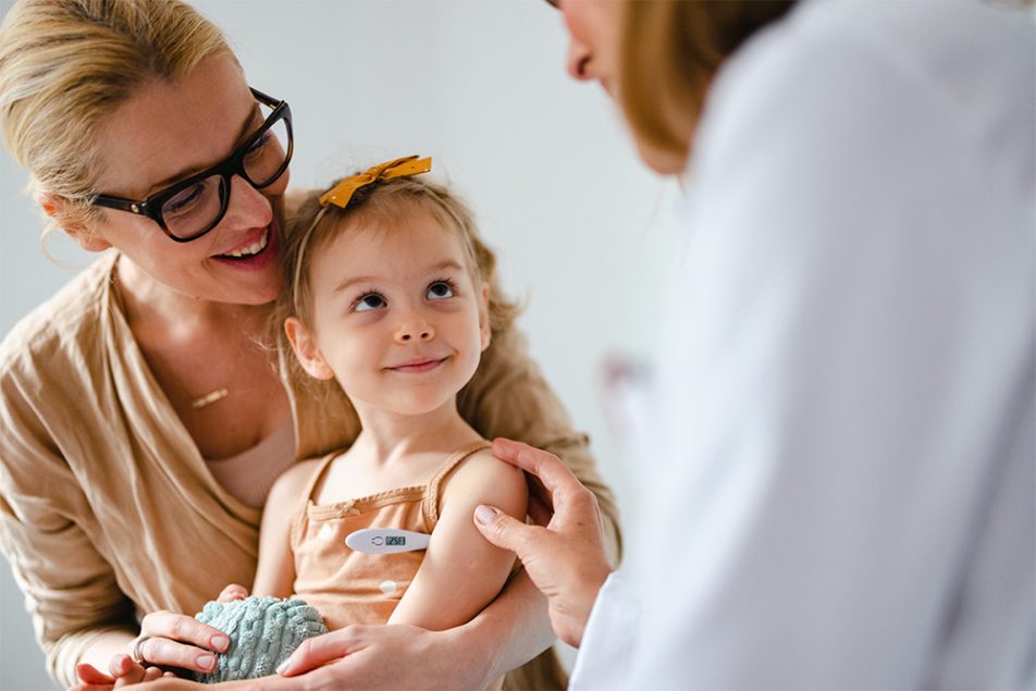 Medico pediatra che controlla la temperatura della bambina in visita presso il suo studio e che ha diritto all’esenzione ticket