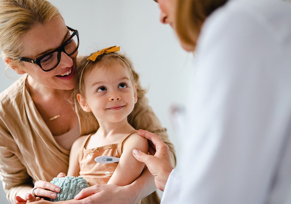 Medico pediatra che controlla la temperatura della bambina in visita presso il suo studio e che ha diritto all’esenzione ticket