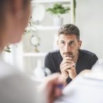 Medico specialista che riferisce ad un parente del paziente l’evidenza dei segnali che la chemioterapia cui è sottoposto il proprio caro sta funzionando