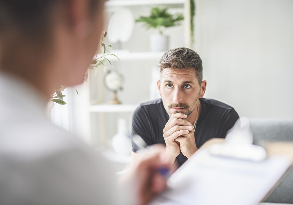 Medico specialista che riferisce ad un parente del paziente l’evidenza dei segnali che la chemioterapia cui è sottoposto il proprio caro sta funzionando