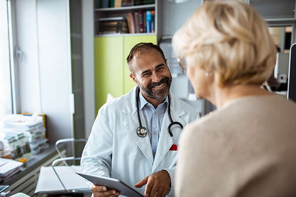 Medico specialista che sorride alla paziente in visita presso il suo studio usufruendo dell’esenzione E01