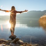 Donna su una pietra davanti a un lago, che trova l'equilibro per i suoi ormoni femminili