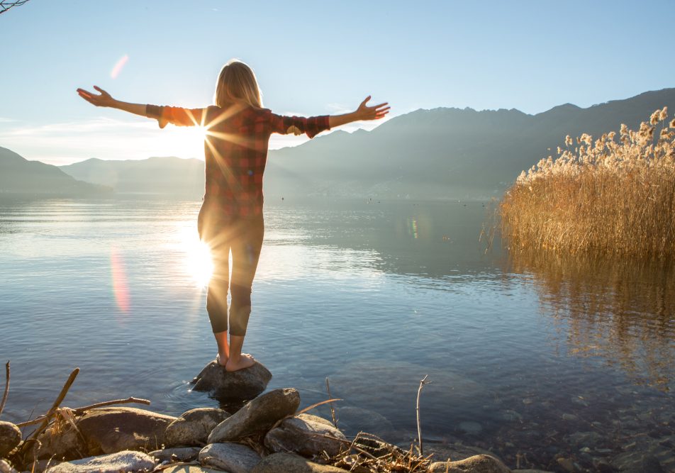 Donna su una pietra davanti a un lago, che trova l'equilibro per i suoi ormoni femminili