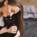 Padrona che coccola affettuosamente il suo gatto nero affetto da pancreatite, seduti insieme in camera da letto