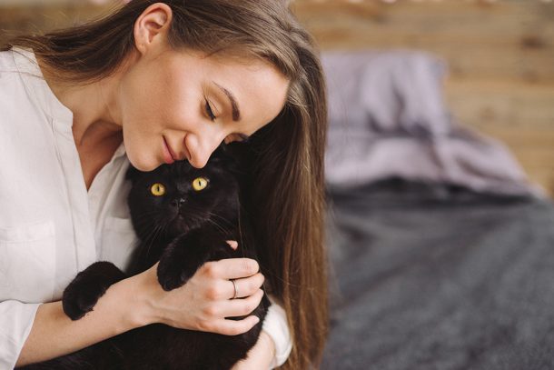 padrona-coccolando-gatto-con-pancreatite Padrona che coccola affettuosamente il suo gatto nero affetto da pancreatite, seduti insieme in camera da letto