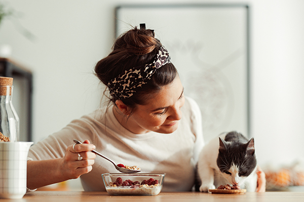 Padrona che cura amorevolmente il suo gatto affetto da diarrea somministrandogli alimenti consigliati dal veterinario, un classico esempio dei possibili rimedi naturali
