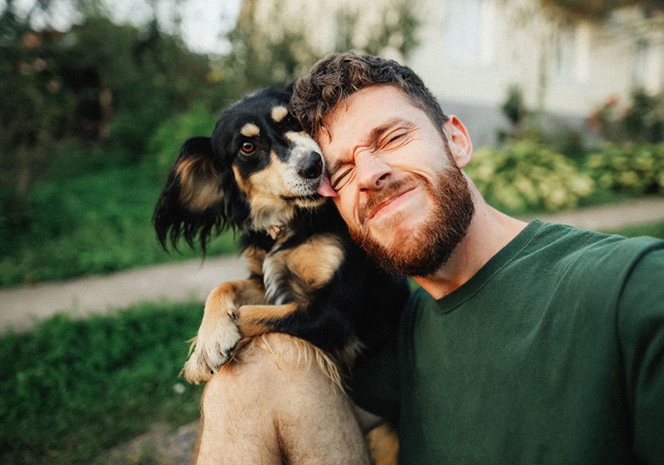 Padrone che gioca insieme al suo cane al parco, scattandosi insieme un selfie per celebrare la guarigione dal parvovirus