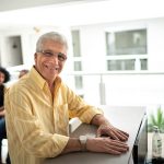 Paziente senior alla reception della clinica medica che sporge alla segretaria l’esenzione per patologia di cui beneficia