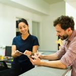 Paziente alla reception della clinica sanitaria insieme all’infermiera che sta firmando il consenso per eseguire gli esami al fegato