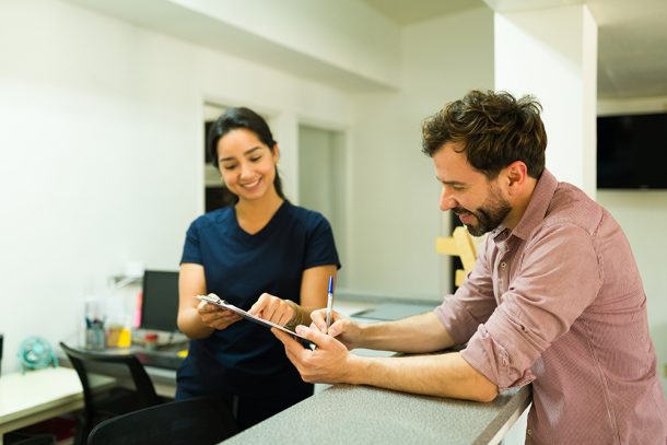 paziente-alla-reception-della-clinica-sanitaria-firmando-consenso-per-esami-fegato Paziente alla reception della clinica sanitaria insieme all’infermiera che sta firmando il consenso per eseguire gli esami al fegato