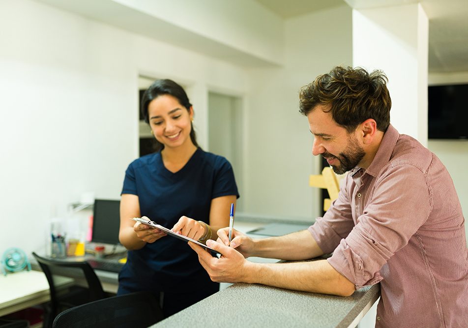 Paziente alla reception della clinica sanitaria insieme all’infermiera che sta firmando il consenso per eseguire gli esami al fegato