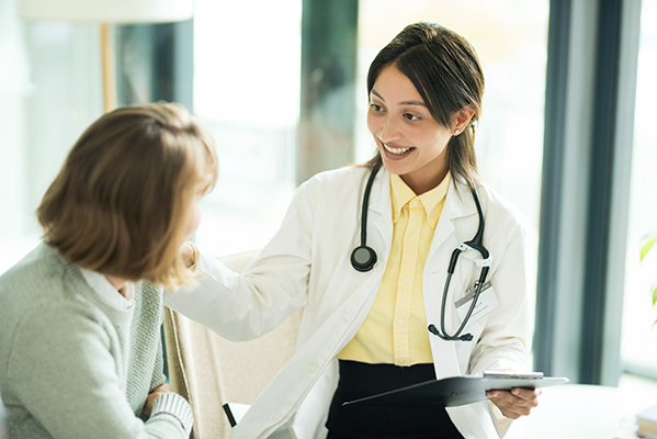 Paziente che gode dell’esenzione ticket pone domande alla dottoressa in camice bianco nel reparto ospedaliero