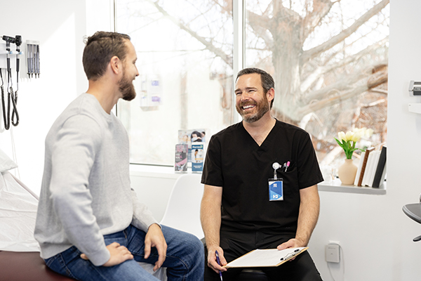 Giovane paziente insieme al medico curante che conversano serenamente alla ricerca di una cura definitiva contro l’herpes genitale