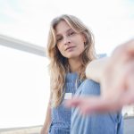 Ragazza su una terrazza cittadina, dopo essere stata sottoposta ad un trapianto, che lancia un messaggio di incoraggiamento con una mano protesa in avanti