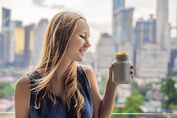 Ragazza sul balcone con vista sui grattacieli che beneficia delle proprietà dei semi di chia attraverso l’apporto di questo prezioso nutriente nella sua dieta