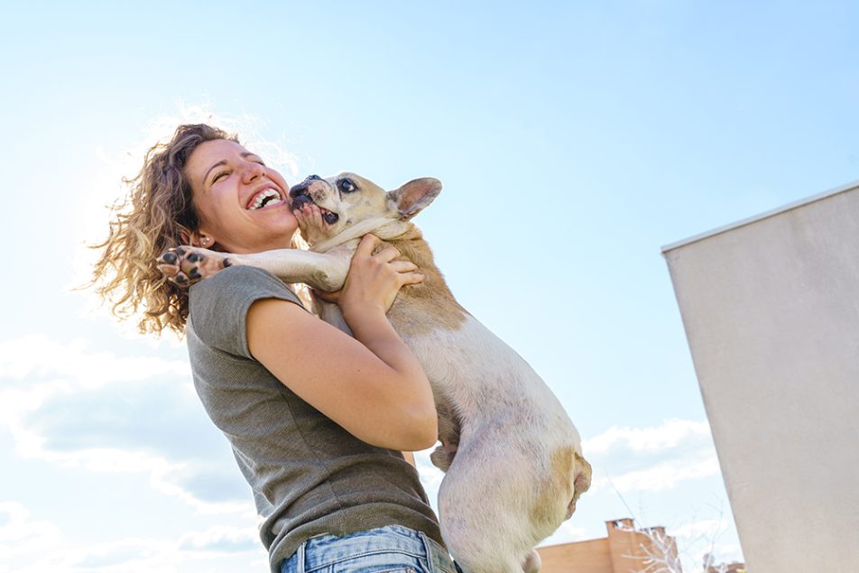 Ragazza in passeggiata felice di tenere in braccio il suo animale domestico, un simpatico e affettuoso cane bulldog