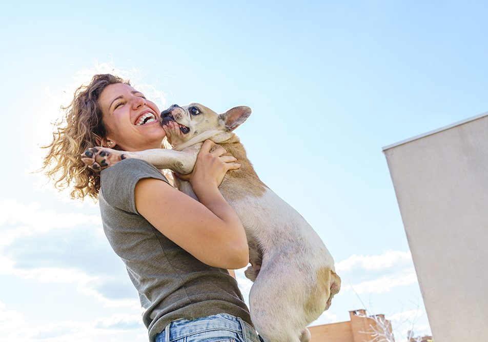 Ragazza in passeggiata felice di tenere in braccio il suo animale domestico, un simpatico e affettuoso cane bulldog