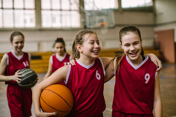 Ragazzine amiche sul campo da basket, uno sport che favorisce la loro salute generale e l’incremento del benessere psicofisico
