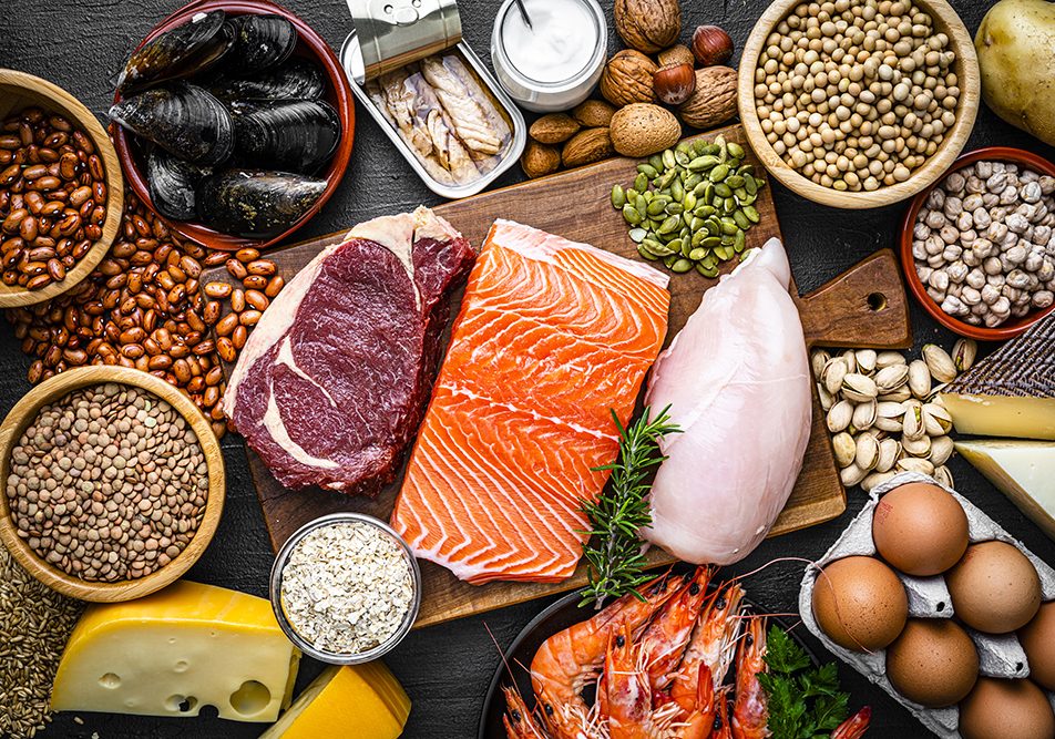 tavola-con-alimenti-ricchi-di-proteine Tavola imbandita con alimenti ricchi di proteine, tra cui: pollo, legumi, formaggi, cozze e frutta secca