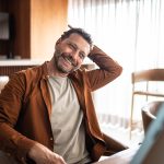 Uomo maturo che allunga il collo mentre guarda sul computer un video tutorial su come prendersi cura dei sintomi della cervicale