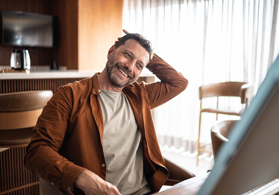 Uomo maturo che allunga il collo mentre guarda sul computer un video tutorial su come prendersi cura dei sintomi della cervicale