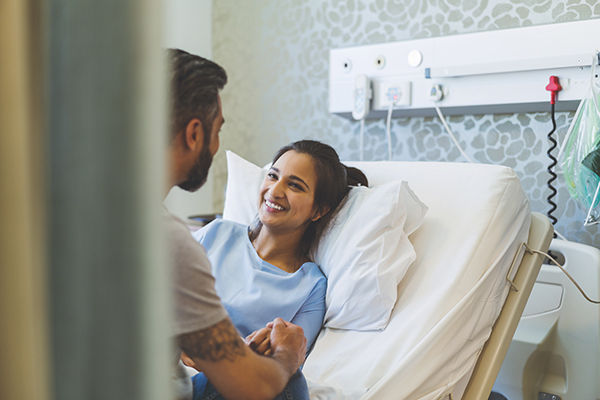 Uomo che rallegra la propria compagna in ospedale, la quale è sottoposta alla chemioterapia ogni 21 giorni