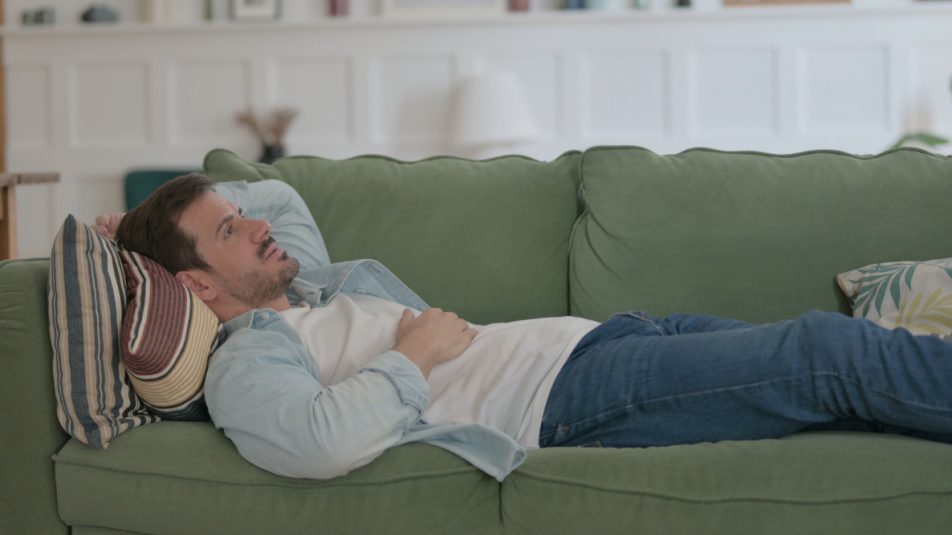 Uomo sdraiato sul suo divano con sintomi pancreatite