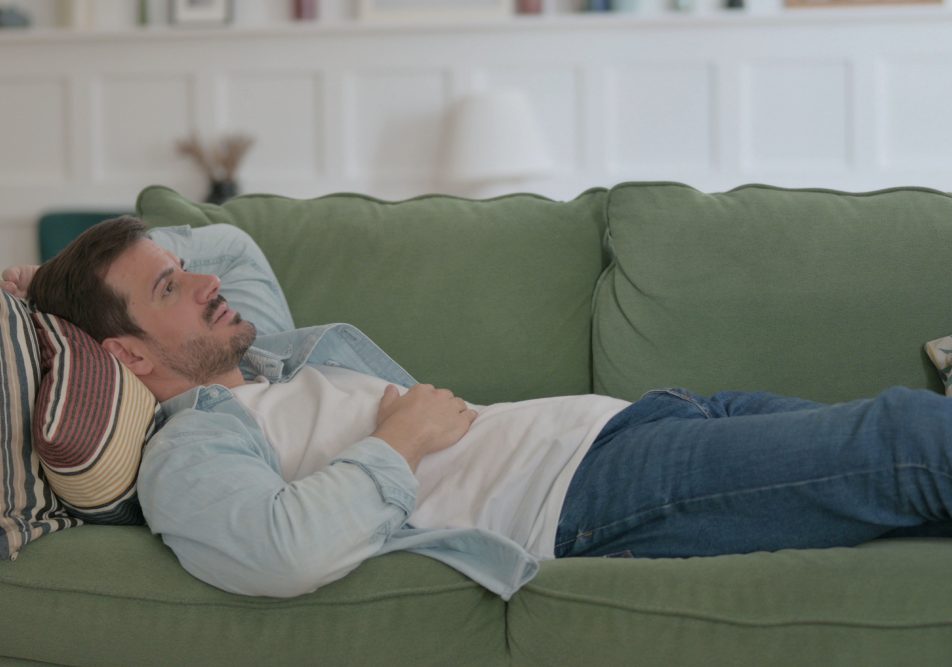 Uomo sdraiato sul suo divano con sintomi pancreatite