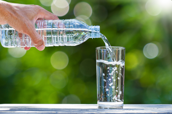 Donna si versa acqua nel bicchiere perché bere molta acqua aiuta a ridurre il rischio del tumore alla vescica