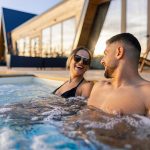 Coppia in una vasca idromassaggio della spa che si gode gli effetti di una balneoterapia osservando il tramonto