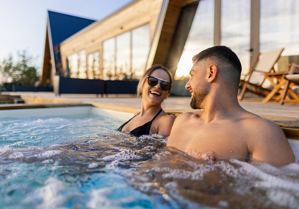 Coppia in una vasca idromassaggio della spa che si gode gli effetti di una balneoterapia osservando il tramonto