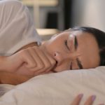 Donna ammalata che tossisce a letto durante una notte convissuta con i disturbi del sonno