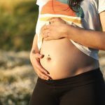 Giovane donna durante il suo primo trimestre di gravidanza che soffre di perdite da impianto e trae beneficio da una passeggiata all’aperto