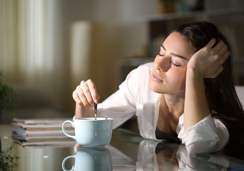 donna-assonnata-al-mattino-riflettendo-su-dormire-poco-conseguenze-psicologiche Al mattino, una donna mescola il caffè in cucina, mentre riflette sulle conseguenze psicologiche del dormire poco