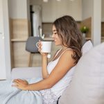 Giovane donna sul suo letto beve camomilla come tisana per dormire
