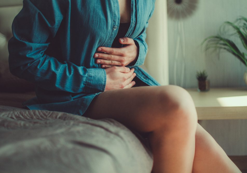 donna-che-soffre-di-cistite-emorragica Donna seduta sul letto con le mani sull'addome a causa della cistite emorragica