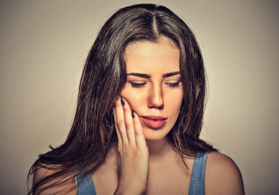 Donna si tocca la guancia con la mano a causa di un ascesso dentale