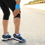 Donna con flebite durante una camminata leggera su una strada asfaltata che si ferma per via del dolore al ginocchio