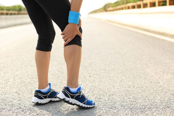 Donna con flebite durante una camminata leggera su una strada asfaltata che si ferma per via del dolore al ginocchio