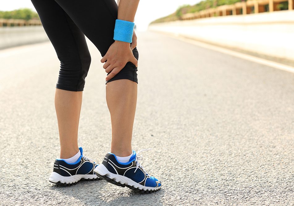Donna con flebite durante una camminata leggera su una strada asfaltata che si ferma per via del dolore al ginocchio