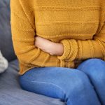 Donna con dolore addominale, tra i sintomi comuni della neoplasia del pancreas