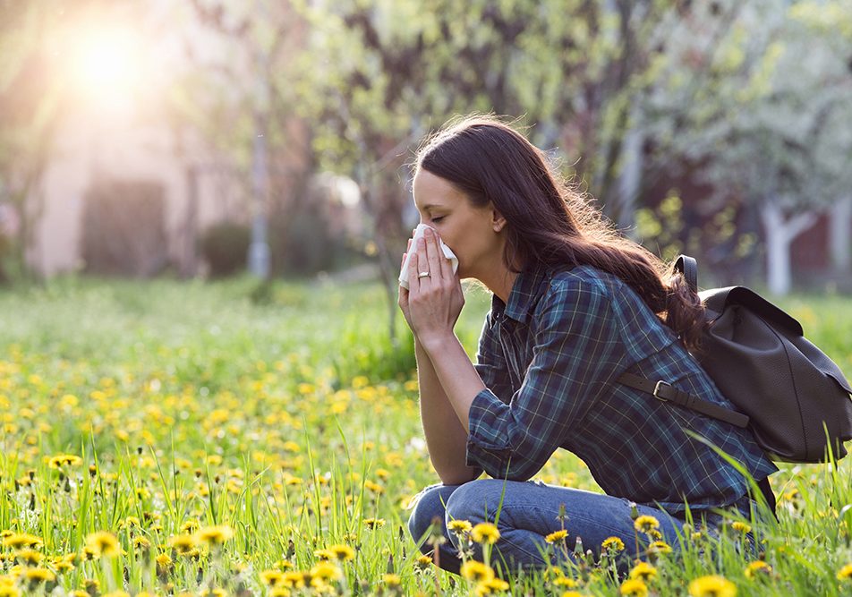 donna-con-rinite-allergica-su-prato-fiorito Donna che soffre di rinite allergica in un campo fiorito durante una passeggiata primaverile
