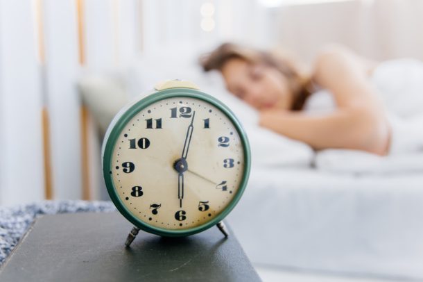 donna-con-ritmo-circadiano-regolare Sveglia in primo piano e donna con ritmo circadiano regolare che dorme nel suo letto