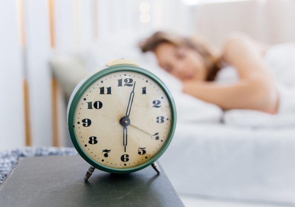 donna-con-ritmo-circadiano-regolare Sveglia in primo piano e donna con ritmo circadiano regolare che dorme nel suo letto