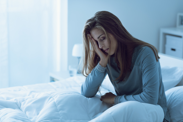 Donna seduta nel suo letto con ritmo circadiano sballato che soffre di insonnia