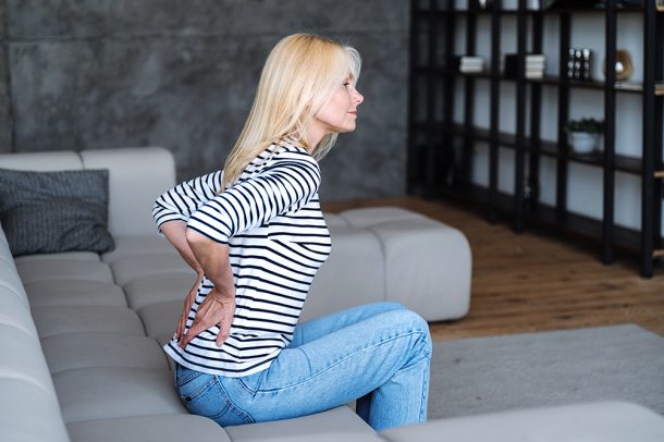 donna-con-sospetta-neoplasia-renale-accusando-dolore-lombare Donna seduta sul divano di casa con sospetta neoplasia renale, che accusa dolore alla schiena nella regione lombare