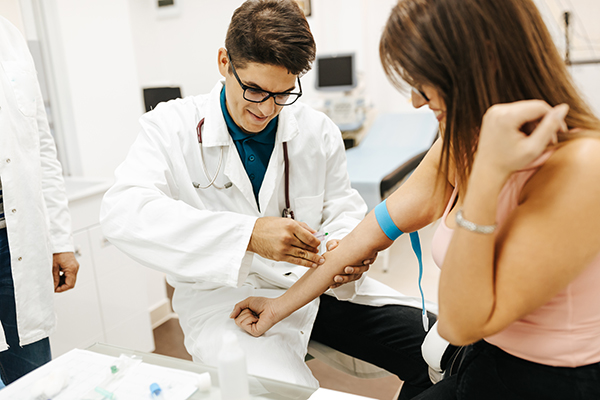 Giovane donna con sintomi di neoplasia mieloproliferativa presso lo studio del medico specialista, che si sottopone a esami del sangue e analisi genetiche per approfondimenti sulla sua condizione