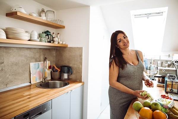 Donna incinta in cucina che prepara un pasto nutriente ed equilibrato per prevenire la cistite in gravidanza