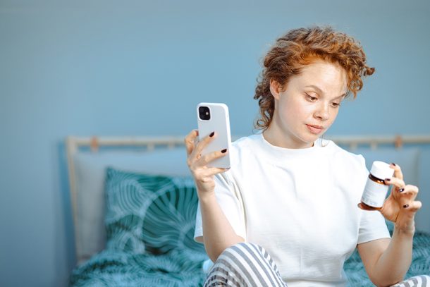 Donna a letto che riceve dal medico, per via telefonica, un consulto sulla reazione allergica che sta riscontrando sulla pelle